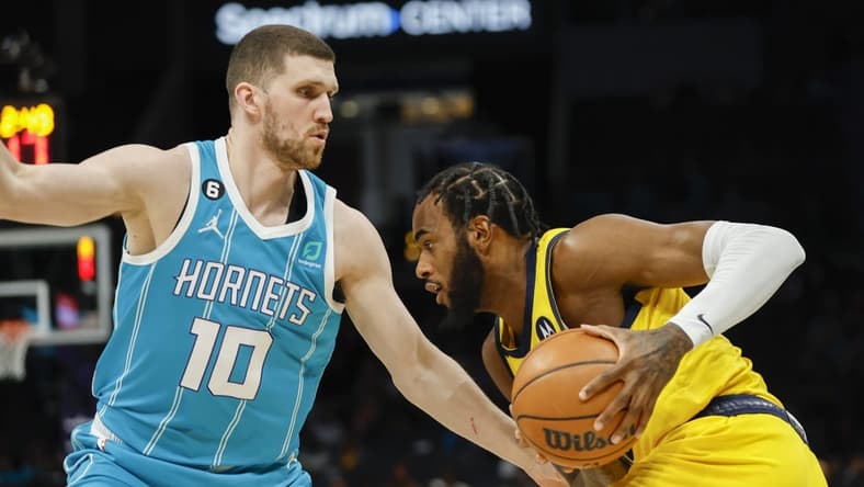 Mar 20, 2023; Charlotte, North Carolina, USA; Indiana Pacers forward Oshae Brissett (12) drives against Charlotte Hornets guard Svi Mykhailiuk (10) during the first half at Spectrum Center. Mandatory Credit: Nell Redmond-USA TODAY Sports