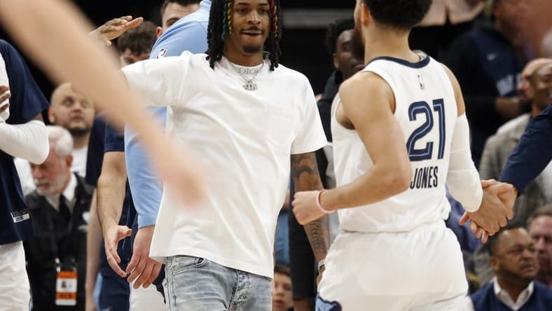 Mar 20, 2023; Memphis, Tennessee, USA; Memphis Grizzlies guard Ja Morant (left) reacts with guard Tyus Jones (21) during a timeout during the second half against the Dallas Mavericks at FedExForum. Mandatory Credit: Petre Thomas-USA TODAY Sports