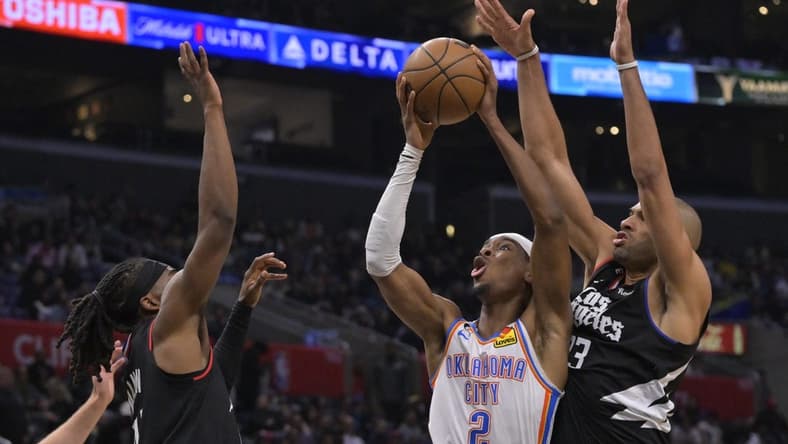 Mar 23, 2023; Los Angeles, California, USA; Oklahoma City Thunder guard Shai Gilgeous-Alexander (2) shoots between Los Angeles Clippers guard Terance Mann (14) and forward Nicolas Batum (33) in the second half at Crypto.com Arena. Mandatory Credit: Jayne Kamin-Oncea-USA TODAY Sports
