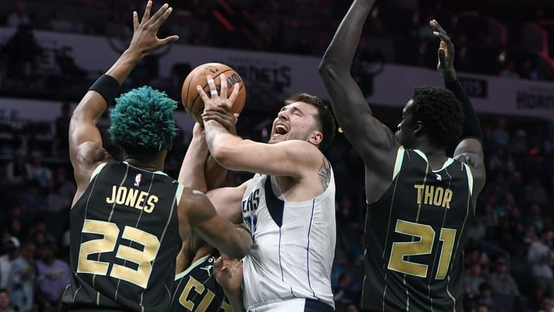 Mar 26, 2023; Charlotte, North Carolina, USA;  Dallas Mavericks guard Luka Doncic (77) shoots as he is defended by Charlotte Hornets forward center Kai Jones (23) and forward JT Thor (21) during the first half at the Spectrum Center. Mandatory Credit: Sam Sharpe-USA TODAY Sports