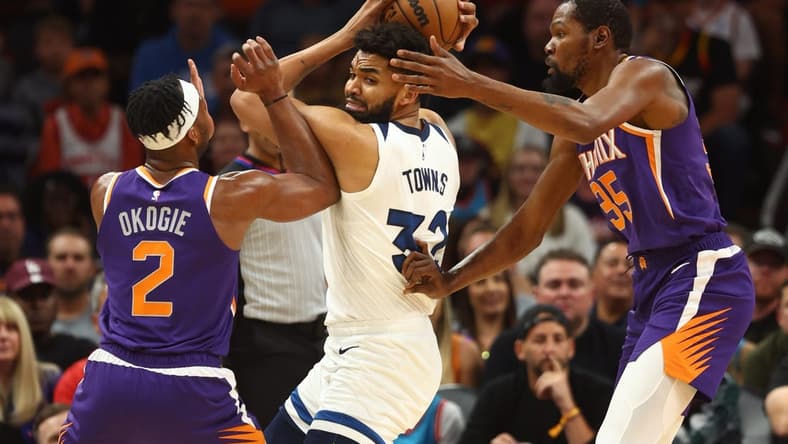 Mar 29, 2023; Phoenix, Arizona, USA; Minnesota Timberwolves center Karl-Anthony Towns (32) controls the ball against Phoenix Suns forward Josh Okogie (2) and Kevin Durant (35) in the first half at Footprint Center. Mandatory Credit: Mark J. Rebilas-USA TODAY Sports