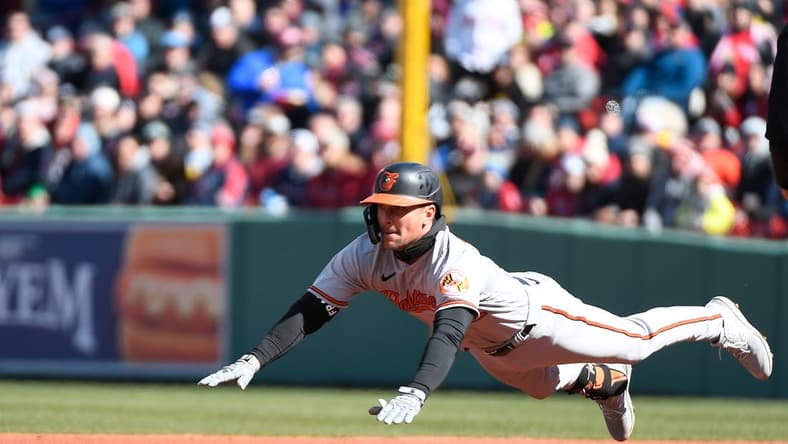 Mar 30, 2023; Boston, Massachusetts, USA; Baltimore Orioles second baseman Adam Frazier (12) dives for second base against the Boston Red Sox  at Fenway Park. Mandatory Credit: Eric Canha-USA TODAY Sports
