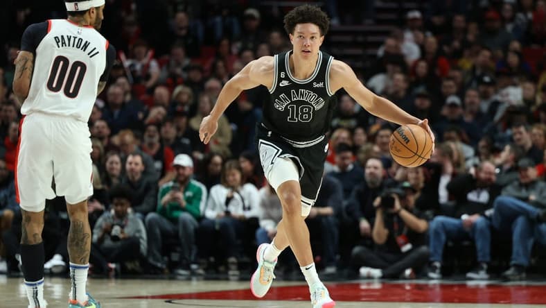 Jan 23, 2023; Portland, Oregon, USA; San Antonio Spurs forward Isaiah Roby (18) dribbles past Portland Trail Blazers guard Gary Payton II (00) in the second half at Moda Center. Mandatory Credit: Jaime Valdez-USA TODAY Sports
