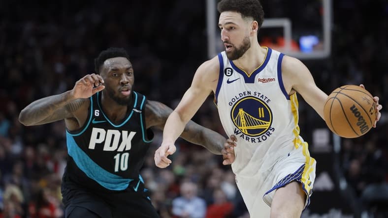 Feb 8, 2023; Portland, Oregon, USA; Golden State Warriors shooting guard Klay Thompson (11) dribbles the ball as Portland Trail Blazers small forward Nassir Little (10) defends during the second half at Moda Center. Mandatory Credit: Soobum Im-USA TODAY Sports