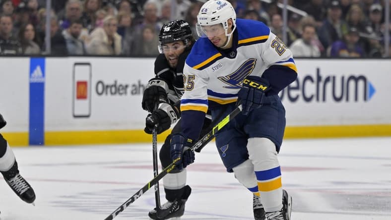 Mar 26, 2023; Los Angeles, California, USA; St. Louis Blues center Jordan Kyrou (25) and Los Angeles Kings left wing Alex Iafallo (19) battle for the puck in the third period at Crypto.com Arena. Mandatory Credit: Jayne Kamin-Oncea-USA TODAY Sports