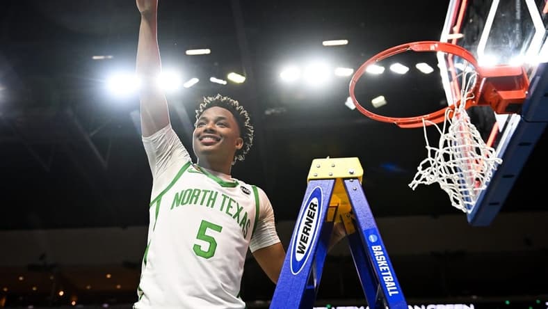 Mar 30, 2023; Las Vegas, NV, USA;  North Texas Mean Green guard Tylor Perry (5) cuts the net after defeating the UAB Blazers to win the NIT Championship at Orleans Arena. Mandatory Credit: Candice Ward-USA TODAY Sports