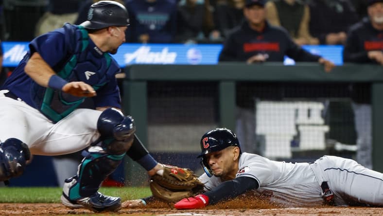 Mar 31, 2023; Seattle, Washington, USA; Cleveland Guardians second baseman Andres Gimenez (0) eludes a tag by Seattle Mariners catcher Cal Raleigh (29) following a second throwing error during the second inning at T-Mobile Park. Mandatory Credit: Joe Nicholson-USA TODAY Sports