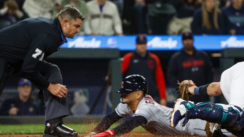 Mar 31, 2023; Seattle, Washington, USA; Cleveland Guardians second baseman Andres Gimenez (0) eludes a tag by Seattle Mariners catcher Cal Raleigh (29) following a second throwing error during the second inning at T-Mobile Park. Home plate umpire Jordan Baker (71) watches before making the call. Mandatory Credit: Joe Nicholson-USA TODAY Sports