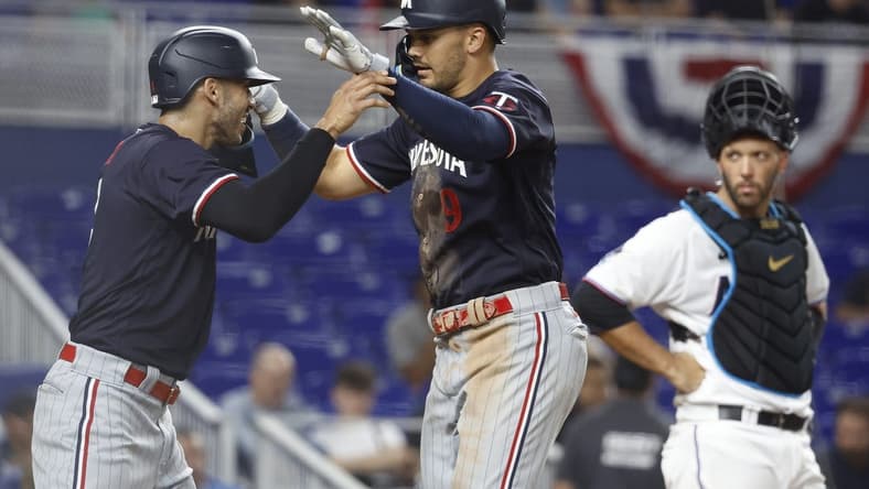 Apr 3, 2023; Miami, Florida, USA;  Miami Marlins catcher Jacob Stallings (58) watches Minnesota Twins left fielder Trevor Larnach (9) and shortstop Carlos Correa celebrate (4) after a two-run home run during the seventh inning at loanDepot Park. Mandatory Credit: Rhona Wise-USA TODAY Sports