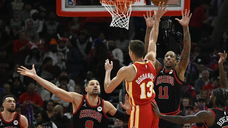 Apr 4, 2023; Chicago, Illinois, USA;  Atlanta Hawks guard Bogdan Bogdanovic (13) shoots against Chicago Bulls center Nikola Vucevic (9) and forward DeMar DeRozan (11) during the first half at the  United Center. Mandatory Credit: Matt Marton-USA TODAY Sports