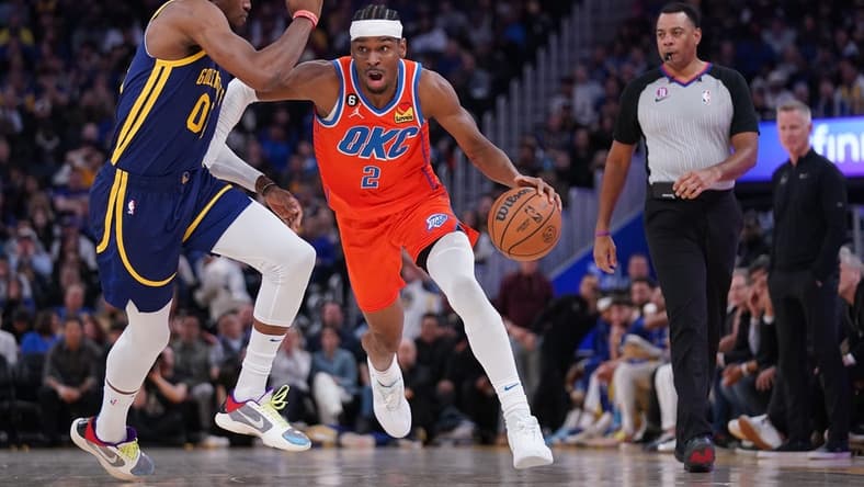 Apr 4, 2023; San Francisco, California, USA; Oklahoma City Thunder guard Shai Gilgeous-Alexander (2) dribbles past Golden State Warriors forward Jonathan Kuminga (00) in the second quarter at the Chase Center. Mandatory Credit: Cary Edmondson-USA TODAY Sports