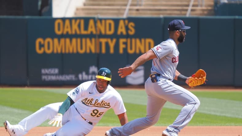 Apr 5, 2023; Oakland, California, USA; Oakland Athletics designated hitter Jesus Aguilar (99) safe at second base as Cleveland Guardians shortstop Amed Rosario (1) is unable to control the ball during the fourth inning at Oakland Coliseum. Mandatory Credit: Kelley L Cox-USA TODAY Sports