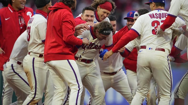 Apr 8, 2023; Philadelphia, Pennsylvania, USA; Philadelphia Phillies second baseman Bryson Stott (5) is mobbed by his teammates to congratulate him for getting the winning hit in the ninth inning against the Cincinnati Reds at Citizens Bank Park. Mandatory Credit: Gregory Fisher-USA TODAY Sports