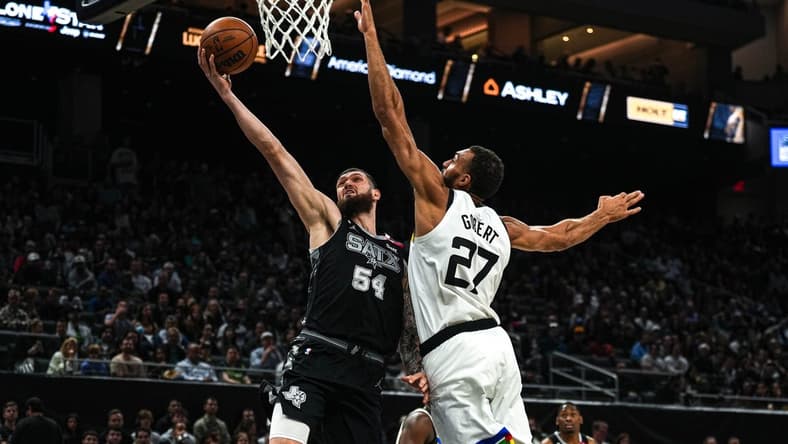 April 8, 2023; Austin, TX, USA; San Antonio Spurs forward Sandro Mamukelashvili (54) shoots past Minnesota Timberwolves center Rudy Gobert (27) during the game at the Moody Center on Saturday, April 8, 2023 in Austin. Mandatory Credit: Aaron E. Martinez-USA TODAY NETWORK
