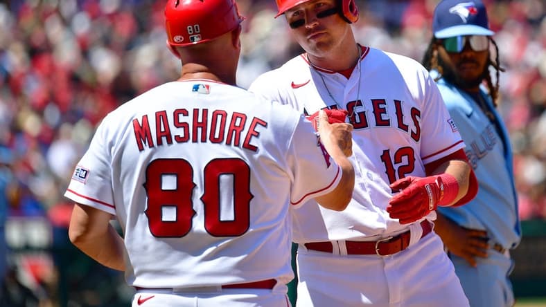 Apr 9, 2023; Anaheim, California, USA; Los Angeles Angels right fielder Hunter Renfroe (12) is greeted by first base coach Damon Mashore (80) after hitting a single against the Toronto Blue Jays during the third inning at Angel Stadium. Mandatory Credit: Gary A. Vasquez-USA TODAY Sports