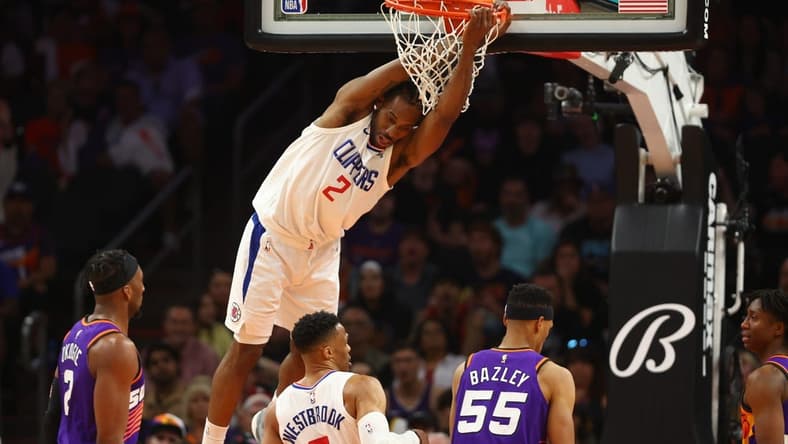 Apr 9, 2023; Phoenix, Arizona, USA; Los Angeles Clippers forward Kawhi Leonard (2) hangs from the rim after a slam dunk against the Phoenix Suns in the second half at Footprint Center. Mandatory Credit: Mark J. Rebilas-USA TODAY Sports