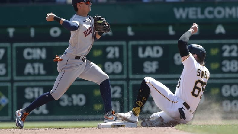Apr 12, 2023; Pittsburgh, Pennsylvania, USA;  Houston Astros second baseman Mauricio Dubon (14) turns a double play over Pittsburgh Pirates center fielder Jack Suwinski (65) during the fifth inning at PNC Park. Mandatory Credit: Charles LeClaire-USA TODAY Sports