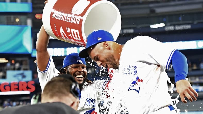 Apr 12, 2023; Toronto, Ontario, CAN;  Toronto Blue Jays right fielder George Springer (4) is doused with ice water by first baseman Vladimir Guerrero Jr. (27) after hitting a walkoff RBI single against the Detroit Tigers in the 10th  inning at Rogers Centre. Mandatory Credit: Dan Hamilton-USA TODAY Sports