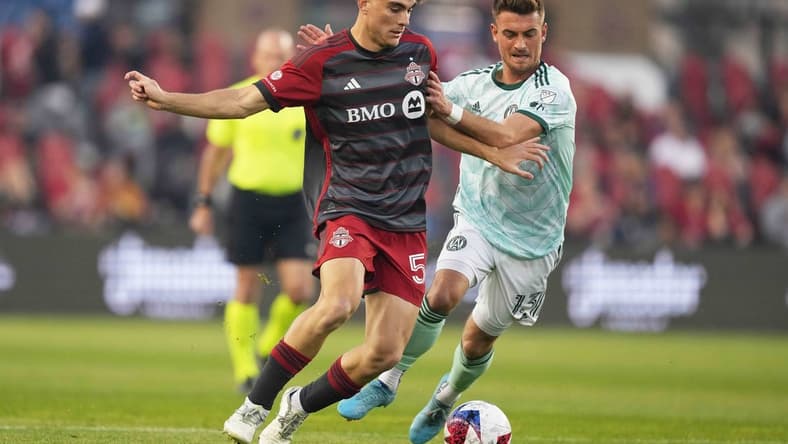 Apr 15, 2023; Toronto, Ontario, CAN; Toronto FC midfielder Alonso Coello (52) battles for the ball with Atlanta United midfielder Amar Sejdic (13) during the first half at BMO Field. Mandatory Credit: Nick Turchiaro-USA TODAY Sports