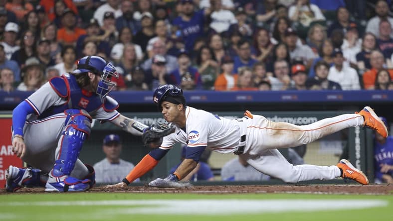 Apr 15, 2023; Houston, Texas, USA; Houston Astros shortstop Jeremy Pena slides safely to score a run as Texas Rangers catcher Jonah Heim attempts to apply a tag during the fourth inning at Minute Maid Park. Mandatory Credit: Troy Taormina-USA TODAY Sports