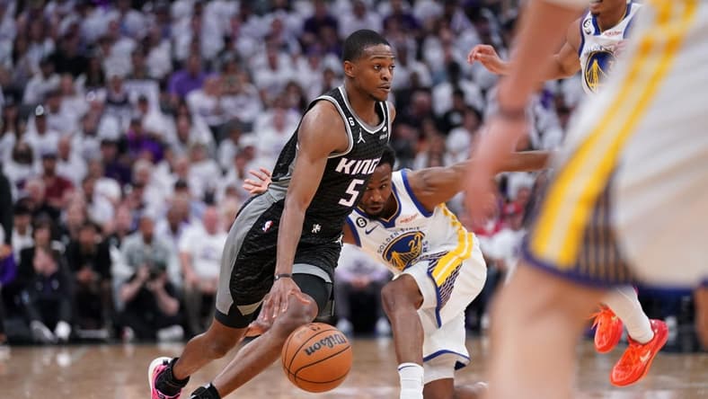 Apr 15, 2023; Sacramento, California, USA; Sacramento Kings guard De'Aaron Fox (5) dribbles past Golden State Warriors forward Andrew Wiggins (22) in the first quarter during game one of the 2023 NBA playoffs at the Golden 1 Center. Mandatory Credit: Cary Edmondson-USA TODAY Sports