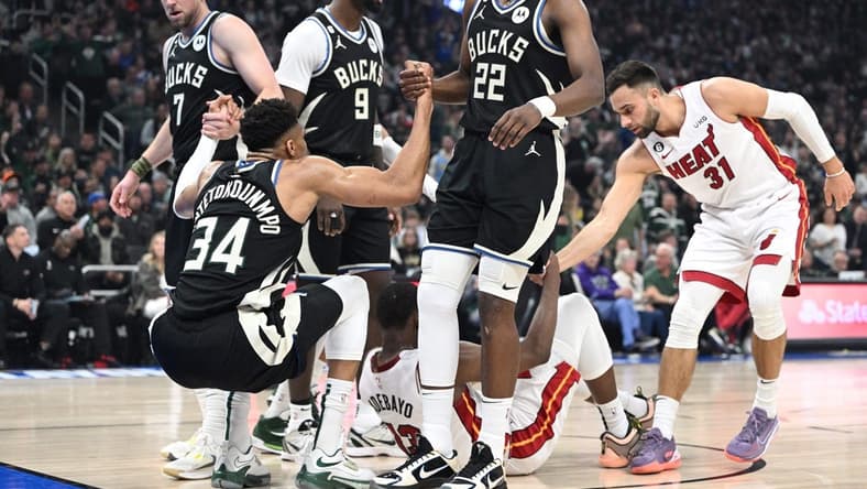 Apr 16, 2023; Milwaukee, Wisconsin, USA; Milwaukee Bucks forward Giannis Antetokounmpo (34) is helped up after a collision in the first half against Miami Heat center Bam Adebayo (13) during game one of the 2023 NBA Playoffs at Fiserv Forum. Mandatory Credit: Michael McLoone-USA TODAY Sports