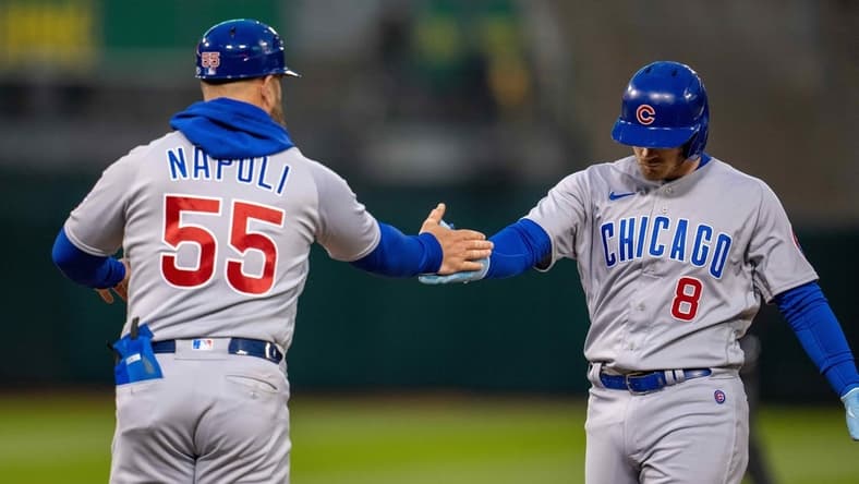 Apr 17, 2023; Oakland, California, USA;  Chicago Cubs left fielder Ian Happ (8) and Chicago Cubs first base coach Mike Napoli (55) celebrate at first base against the Oakland Athletics during the fourth inning at RingCentral Coliseum. Mandatory Credit: Neville E. Guard-USA TODAY Sports
