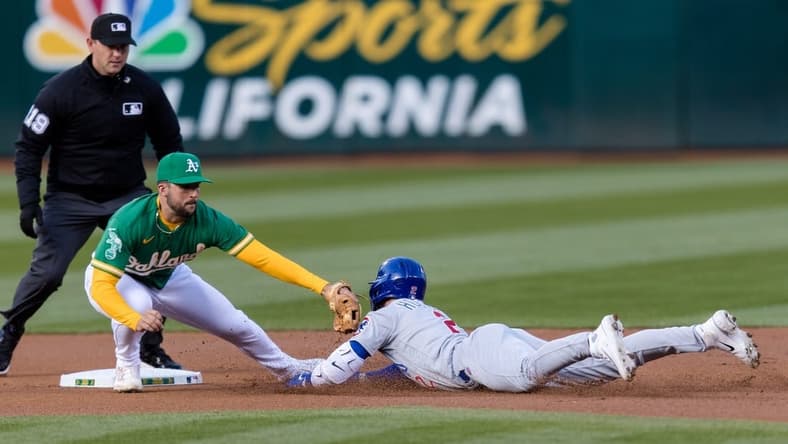 Apr 18, 2023; Oakland, California, USA;  Chicago Cubs second baseman Nico Hoerner (2) dives into second for a double against Oakland Athletics shortstop Kevin Smith (4) during the first inning at RingCentral Coliseum. Mandatory Credit: John Hefti-USA TODAY Sports