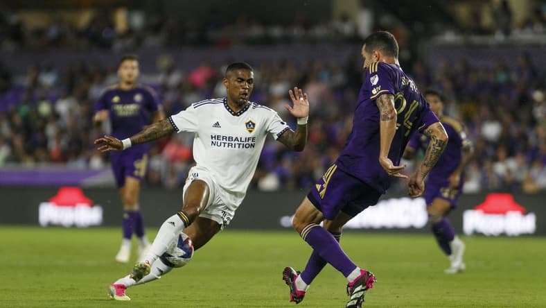 Apr 29, 2023; Orlando, Florida, USA; Orlando City SC defender Kyle Smith (24) passes the ball through the legs of Los Angeles Galaxy midfielder Douglas Costa (10) in the first half at Exploria Stadium. Mandatory Credit: Morgan Tencza-USA TODAY Sports