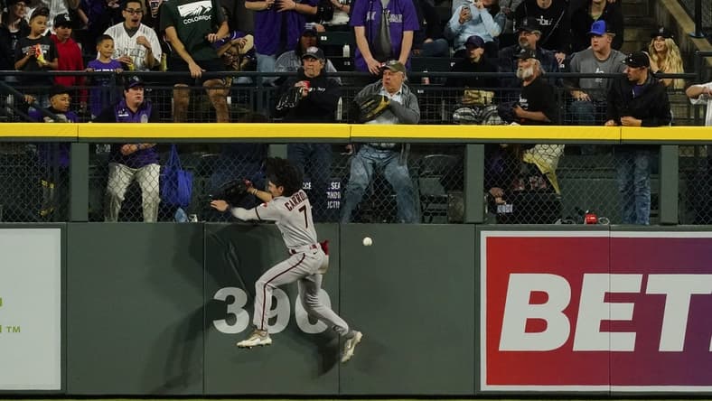 Apr 29, 2023; Denver, Colorado, USA;  Arizona Diamondbacks left fielder Corbin Carroll (7) falls after banging into the outfield wall at Coors Field.  Carroll left the game after the play. Mandatory Credit: Michael Madrid-USA TODAY Sports