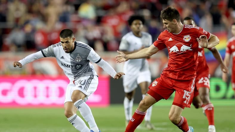 Jun 18, 2022; Harrison, New Jersey, USA; Toronto FC midfielder Alejandro Pozuelo (10) controls the ball against New York Red Bulls defender Sean Nealis (15) during the second half at Red Bull Arena. Mandatory Credit: Brad Penner-USA TODAY Sports