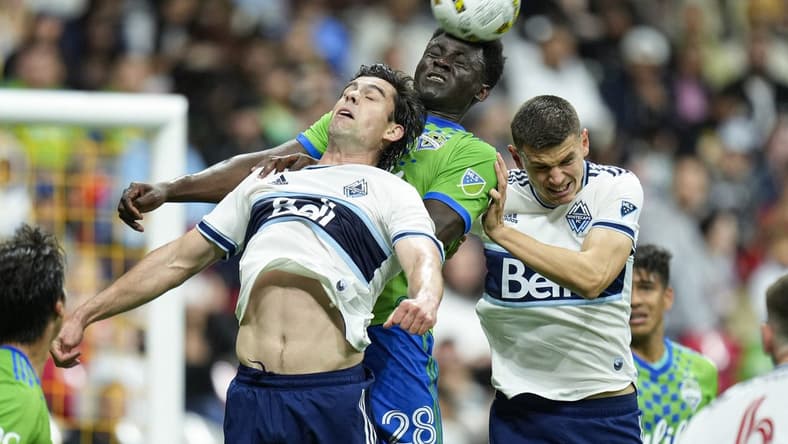 Sep 17, 2022; Vancouver, British Columbia, CAN; Seattle Sounders defender Yeimar Gomez Andrade (28) gets his head on the ball while battling with Vancouver Whitecaps forward Brian White (24) and defender Ranko Veselinovic (4) in the first half at BC Place. Mandatory Credit: Bob Frid-USA TODAY Sports