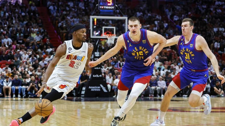 Feb 13, 2023; Miami, Florida, USA; Miami Heat forward Jimmy Butler (22) dribbles the basketball ahead of Denver Nuggets center Nikola Jokic (15) and forward Vlatko Cancar (31) during the second quarter at Miami-Dade Arena. Mandatory Credit: Sam Navarro-USA TODAY Sports