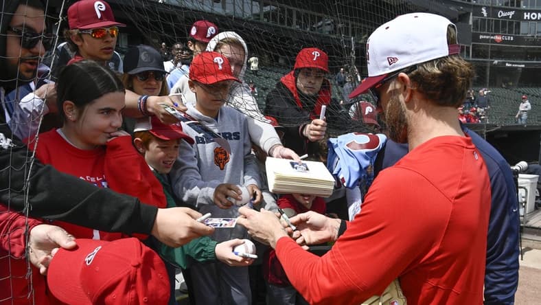 Apr 19, 2023; Chicago, Illinois, USA;   Philadelphia Phillies  Bryce Harper (right) signs autographs for young fans in the stands prior to the game against the Chicago White Sox at Guaranteed Rate Field. Mandatory Credit: Matt Marton-USA TODAY Sports