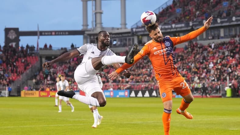Apr 29, 2023; Toronto, Ontario, CAN; Toronto FC forward Charles Sapong (9) battles for the ball against New York City FC forward Kevin O'Toole (22) during the first half at BMO Field. Mandatory Credit: Nick Turchiaro-USA TODAY Sports