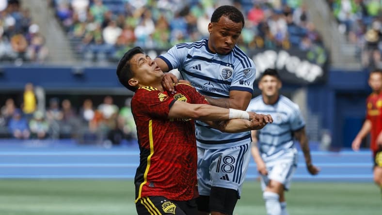 May 7, 2023; Seattle, Washington, USA; Sporting Kansas City defender Logan Ndenbe (18) fouls Seattle Sounders FC forward Fredy Montero (12) during the second half at Lumen Field. Seattle was awarded a penalty kick on the play; the kick was converted for a goal. Mandatory Credit: Joe Nicholson-USA TODAY Sports