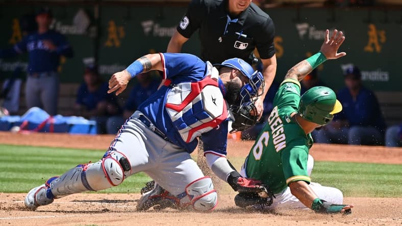 May 13, 2023; Oakland, California, USA; Texas Rangers catcher Sandy Leon (12) tags out Oakland Athletics infielder Jace Peterson (6) during the seventh inning at Oakland-Alameda County Coliseum. Mandatory Credit: Robert Edwards-USA TODAY Sports
