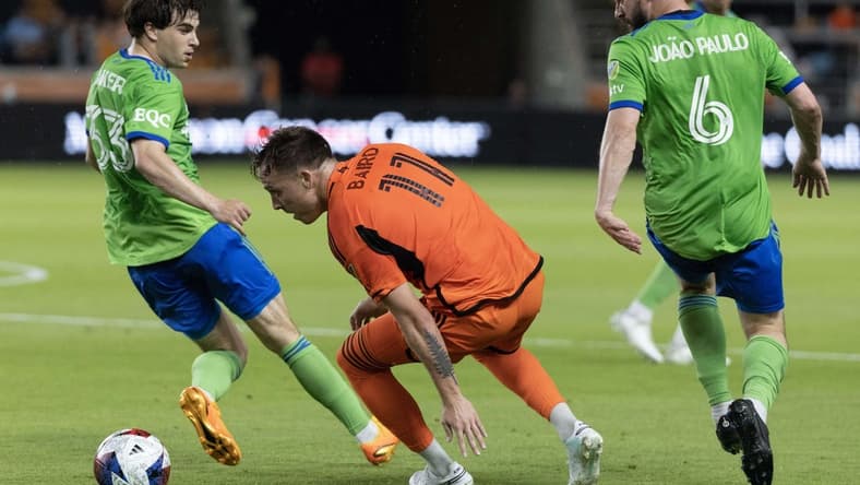 May 13, 2023; Houston, Texas, USA; Houston Dynamo forward Corey Baird (11) dribbles against Seattle Sounders defender Cody Baker (33) and  midfielder Joao Paulo (6)  in the first half at Shell Energy Stadium. Mandatory Credit: Thomas Shea-USA TODAY Sports