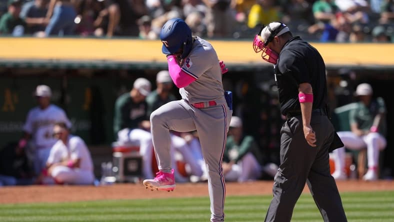 May 14, 2023; Oakland, California, USA; Texas Rangers right fielder Adolis Garcia (center) steps on home plate after hitting a grand slam home run against the Oakland Athletics as home plate umpire Dan Bellino (right) watches during the eighth inning at Oakland-Alameda County Coliseum. Mandatory Credit: Darren Yamashita-USA TODAY Sports