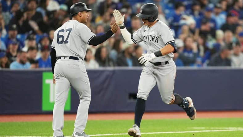 May 18, 2023; Toronto, Ontario, CAN; New York Yankees shortstop Anthony Volpe (11) hits a home run and celebrates with third base coach Luis Rojas (67) against the Toronto Blue Jays during the ninth inning at Rogers Centre. Mandatory Credit: Nick Turchiaro-USA TODAY Sports
