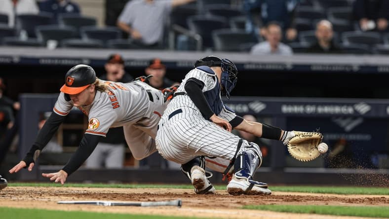 May 24, 2023; Bronx, New York, USA; Baltimore Orioles third baseman Gunnar Henderson (2) dives past New York Yankees catcher Kyle Higashioka (66) to score a run during the seventh inning at Yankee Stadium. Mandatory Credit: Vincent Carchietta-USA TODAY Sports