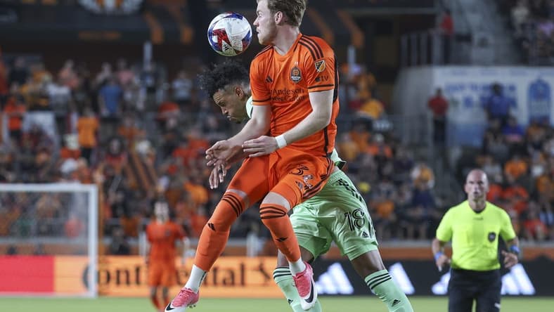 May 27, 2023; Houston, Texas, USA; Houston Dynamo FC forward Thor Ulfarsson (34) attempts to head the ball away from Austin FC defender Julio Cascante (18) during the match at Shell Energy Stadium. Mandatory Credit: Troy Taormina-USA TODAY Sports
