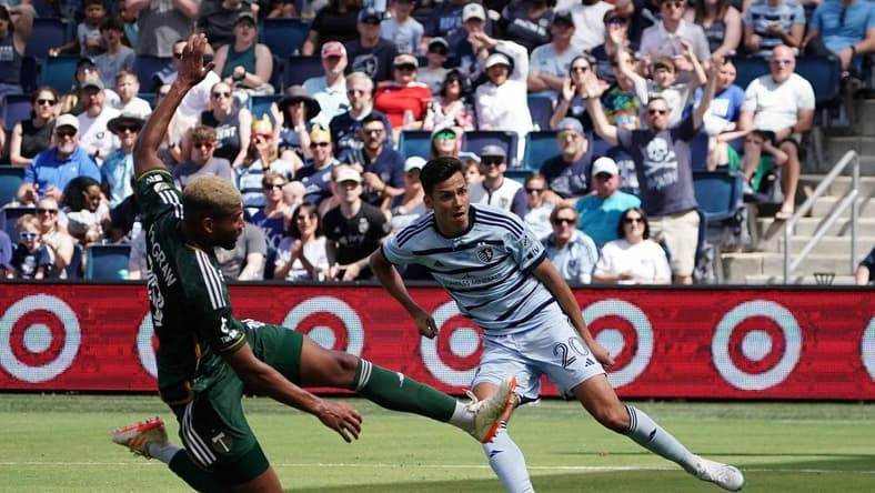 May 28, 2023; Kansas City, Kansas, USA; Sporting Kansas City forward Daniel Salloi (20) shoots the ball against Portland Timbers defender Zac McGraw (18) during the second half at Children's Mercy Park. Mandatory Credit: Denny Medley-USA TODAY Sports