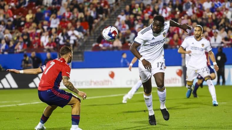 Mar 4, 2023; Frisco, Texas, USA; Los Angeles Galaxy midfielder Chris Mavinga (17) heads teh ball past FC Dallas forward Paul Arriola (7) during the first half at Toyota Stadium. Mandatory Credit: Kevin Jairaj-USA TODAY Sports