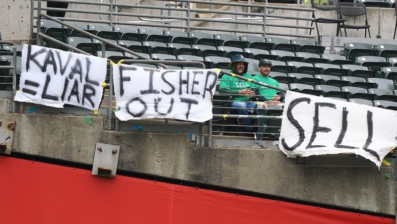 May 28, 2023; Oakland, California, USA; Oakland Athletics fans sit between signs reading Kaval=liar , Fisher out and sell during the first inning against the Houston Astros at Oakland-Alameda County Coliseum. Mandatory Credit: Kelley L Cox-USA TODAY Sports