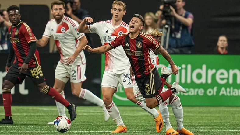 May 31, 2023; Atlanta, Georgia, USA; Atlanta United midfielder Thiago Almada (23) trips over New England Revolution forward Latif Blessing (19) during the first half at Mercedes-Benz Stadium. Mandatory Credit: Dale Zanine-USA TODAY Sports