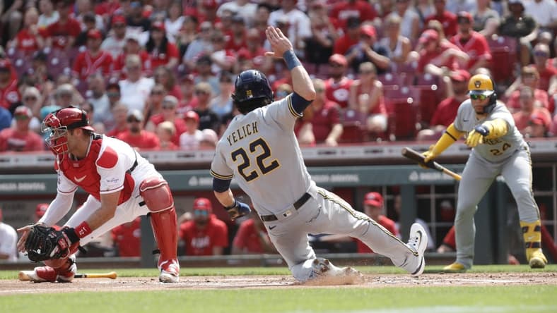 Jun 3, 2023; Cincinnati, Ohio, USA; Milwaukee Brewers left fielder Christian Yelich (22) scores against Cincinnati Reds catcher Curt Casali (12) during the first inning at Great American Ball Park. Mandatory Credit: David Kohl-USA TODAY Sports