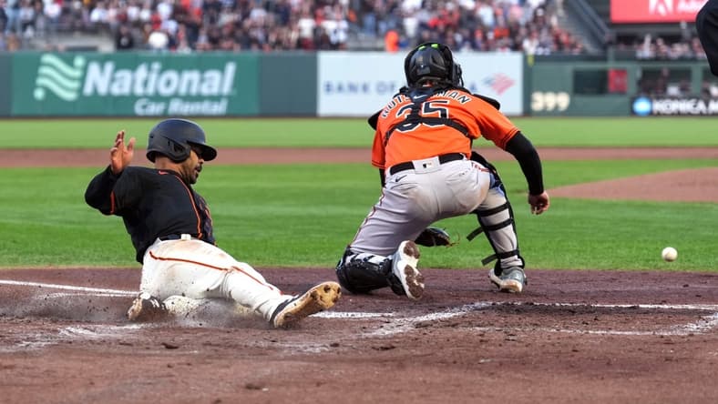 Jun 3, 2023; San Francisco, California, USA; San Francisco Giants first baseman LaMonte Wade Jr. (31) slides into home plate to score a run as Baltimore Orioles catcher Adley Rutschman (35) waits for a throw during the third inning at Oracle Park. Mandatory Credit: Darren Yamashita-USA TODAY Sports