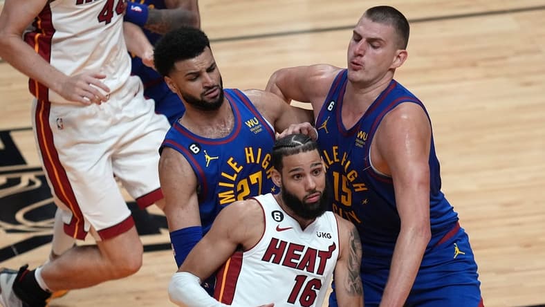 Jun 7, 2023; Miami, Florida, USA; Miami Heat forward Caleb Martin (16) attempts to dribble the ball against Denver Nuggets guard Jamal Murray (27) and center Nikola Jokic (15) during the first quarter in game three of the 2023 NBA Finals at Kaseya Center. Mandatory Credit: Jim Rassol-USA TODAY Sports