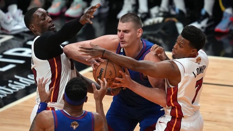 Jun 7, 2023; Miami, Florida, USA; Denver Nuggets center Nikola Jokic (15) grabs a rebound over Miami Heat guard Kyle Lowry (7) and center Bam Adebayo (13) during the second quarter in game three of the 2023 NBA Finals at Kaseya Center. Mandatory Credit: Jim Rassol-USA TODAY Sports